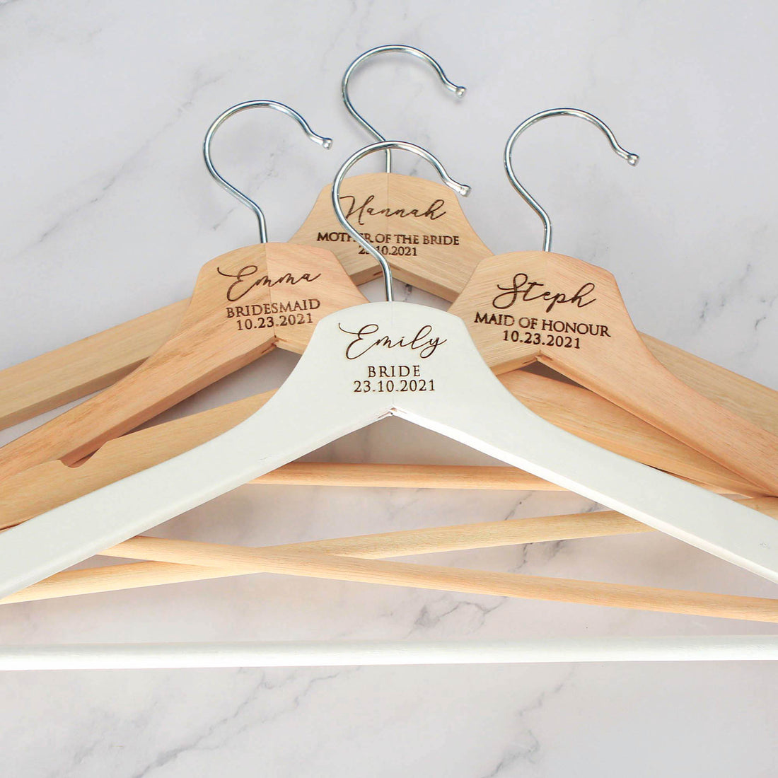 personalised hangers in white and natural wooden colour. The hangers are laser engraved the name, title and date of the wedding