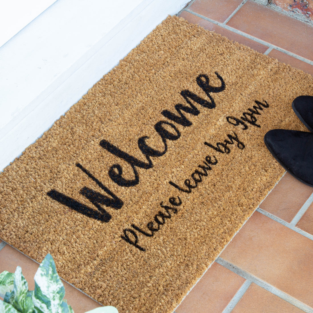 personalised natural coir door mat, written as 'Welcome please leave by 9PM' in black